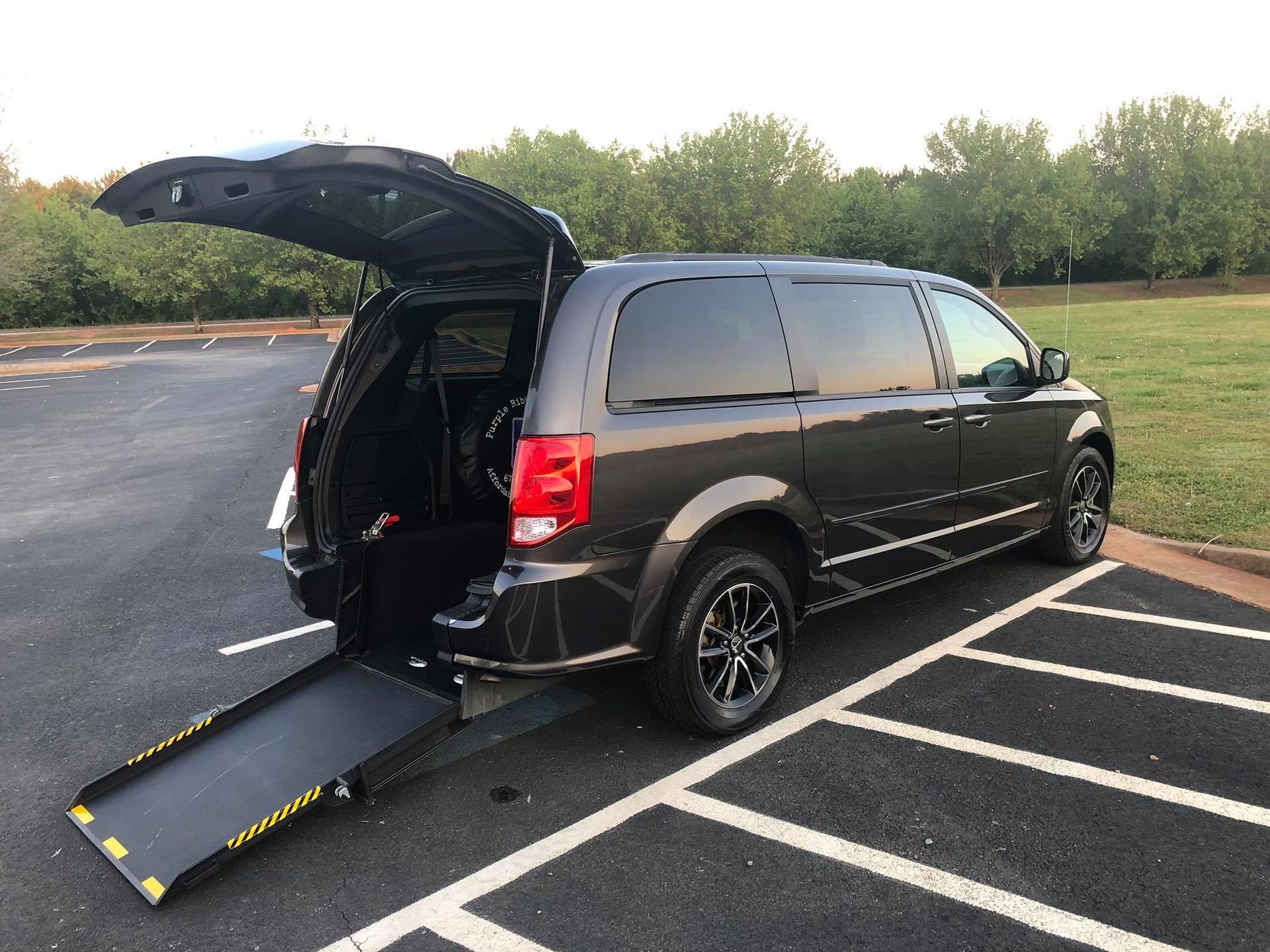 Dark gray handicap accessible van with ramp extended in parking lot.