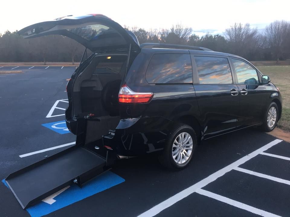 Black wheelchair-accessible minivan in a parking spot with the ramp extended.