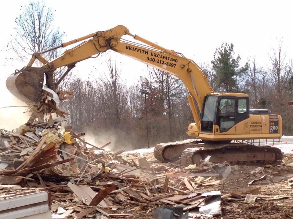 a large yellow excavator is demolishing a building .