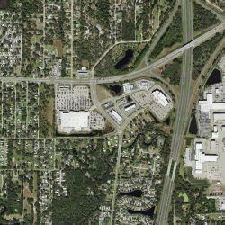 Aerial view of a town with roads, buildings, trees, and a highway.