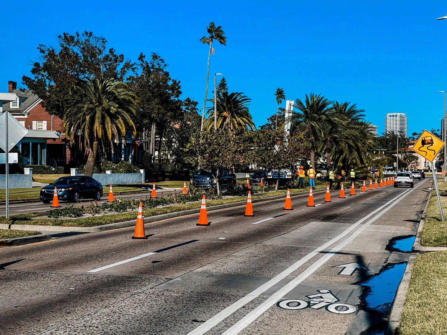 Road construction with orange cones and vehicles on a sunny day.