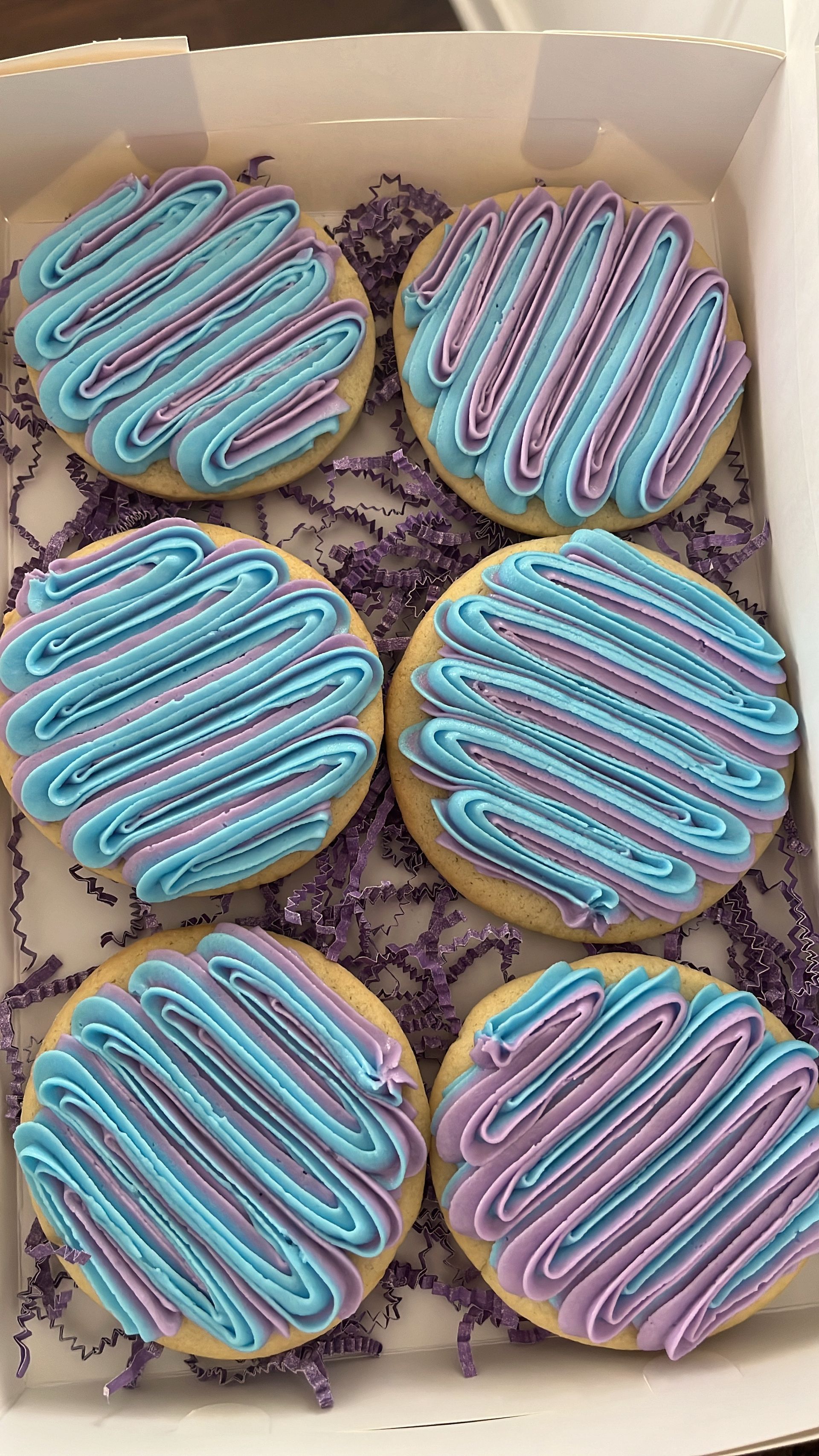 a box of cookies with blue and purple frosting on them