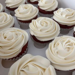 White frosted cupcakes with rose-shaped swirls arranged on a tray