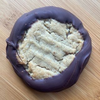 Chocolate-dipped cookie with a crumbly pale center on a wooden surface