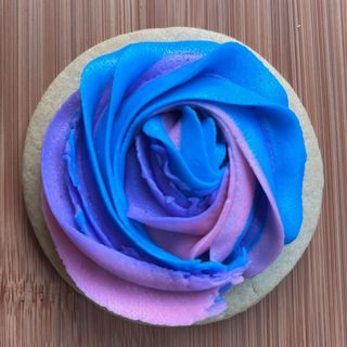 Blue and purple rose-shaped frosting on a round cookie or cake topper