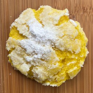 Yellow crumbly dough dusted with white flour on a wooden surface