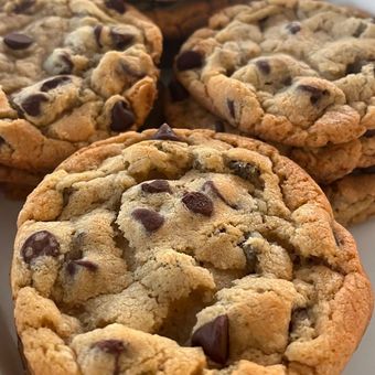 Close-up of gooey chocolate chip cookies stacked together, golden brown and fresh-baked