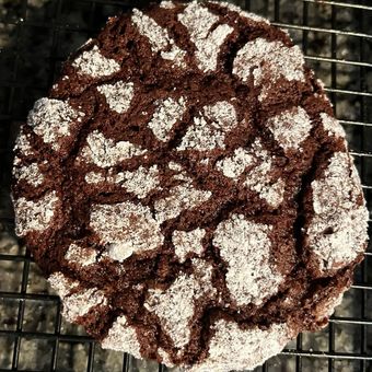 Chocolate crinkle cookie on a wire rack, dusted with powdered sugar.