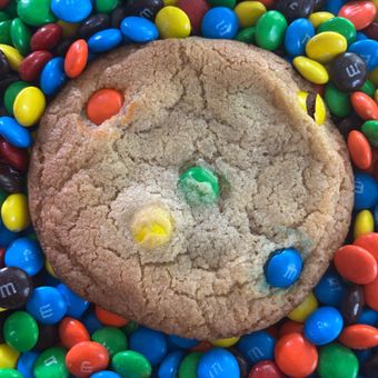 Cookie topped with colorful candy pieces, surrounded by scattered rainbow candies