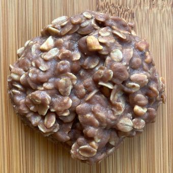 Cluster of glossy brown nuts or seeds bound together on a wooden surface