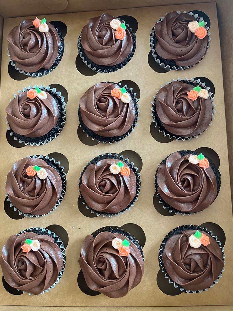 a box of chocolate frosted cupcakes with pumpkins on them