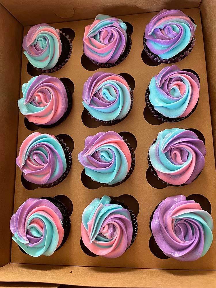 a box of cupcakes with pink, blue, and purple frosting