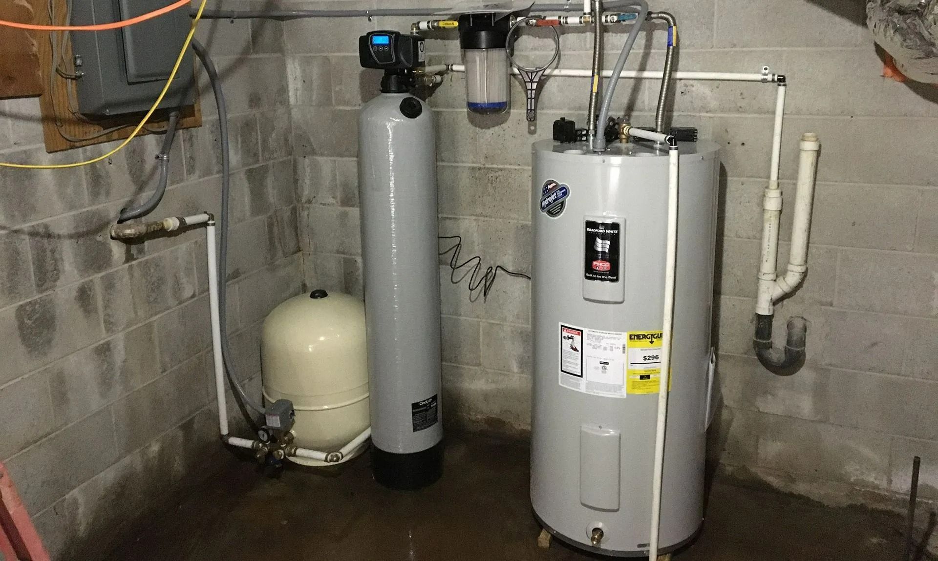 Water softener and heater system in a basement.  Includes a water tank, filter, and pressure tank.