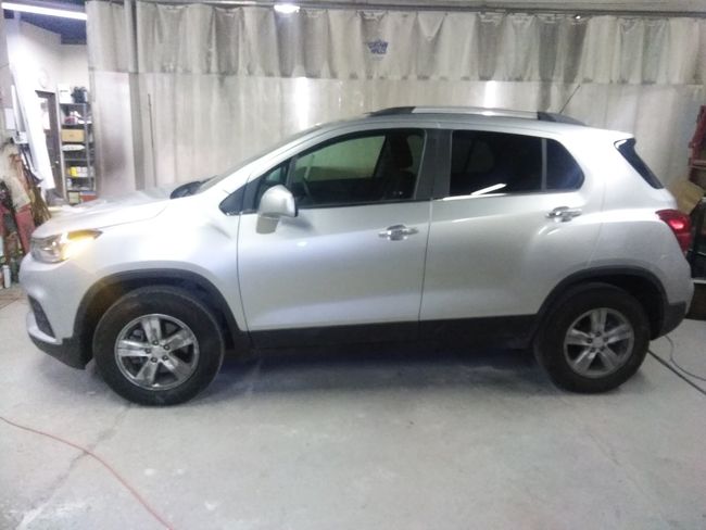 A silver SUV is parked inside an auto shop