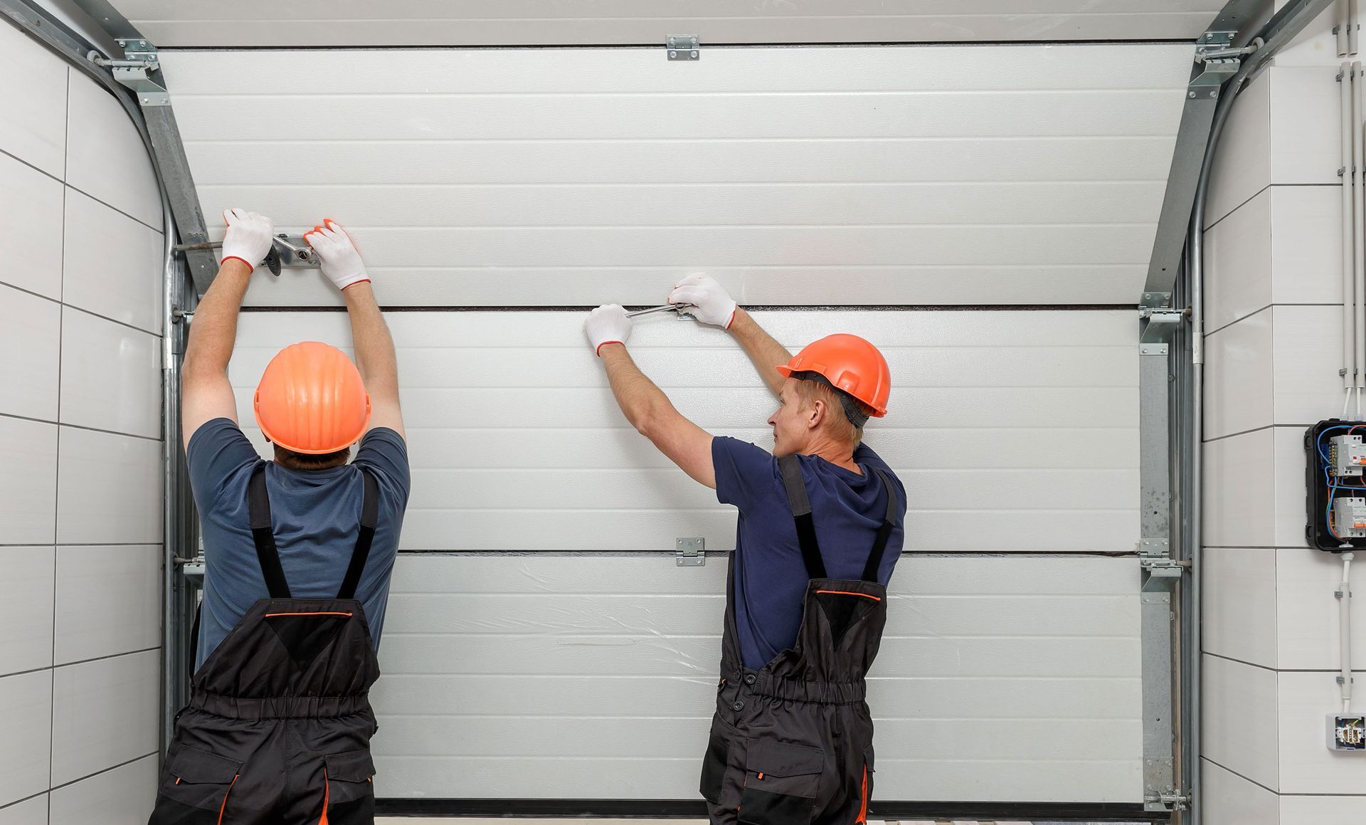 Two men are installing a garage door in a garage.
