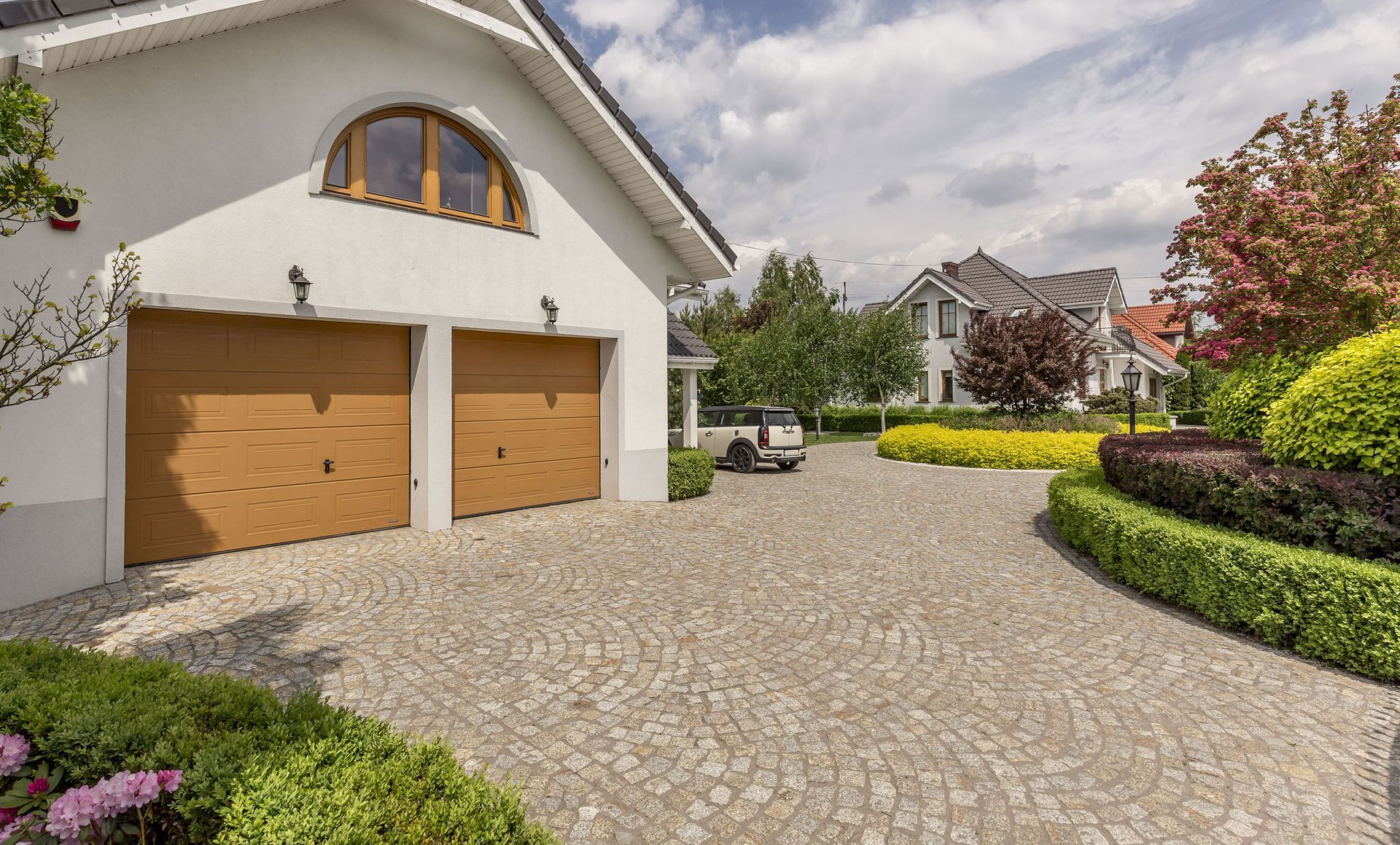 A white house with two garage doors and a car parked in front of it.