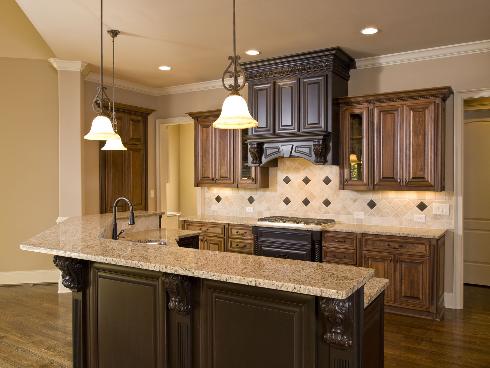 Modern kitchen with dark wood cabinets, granite island, pendant lights, and beige tile backsplash