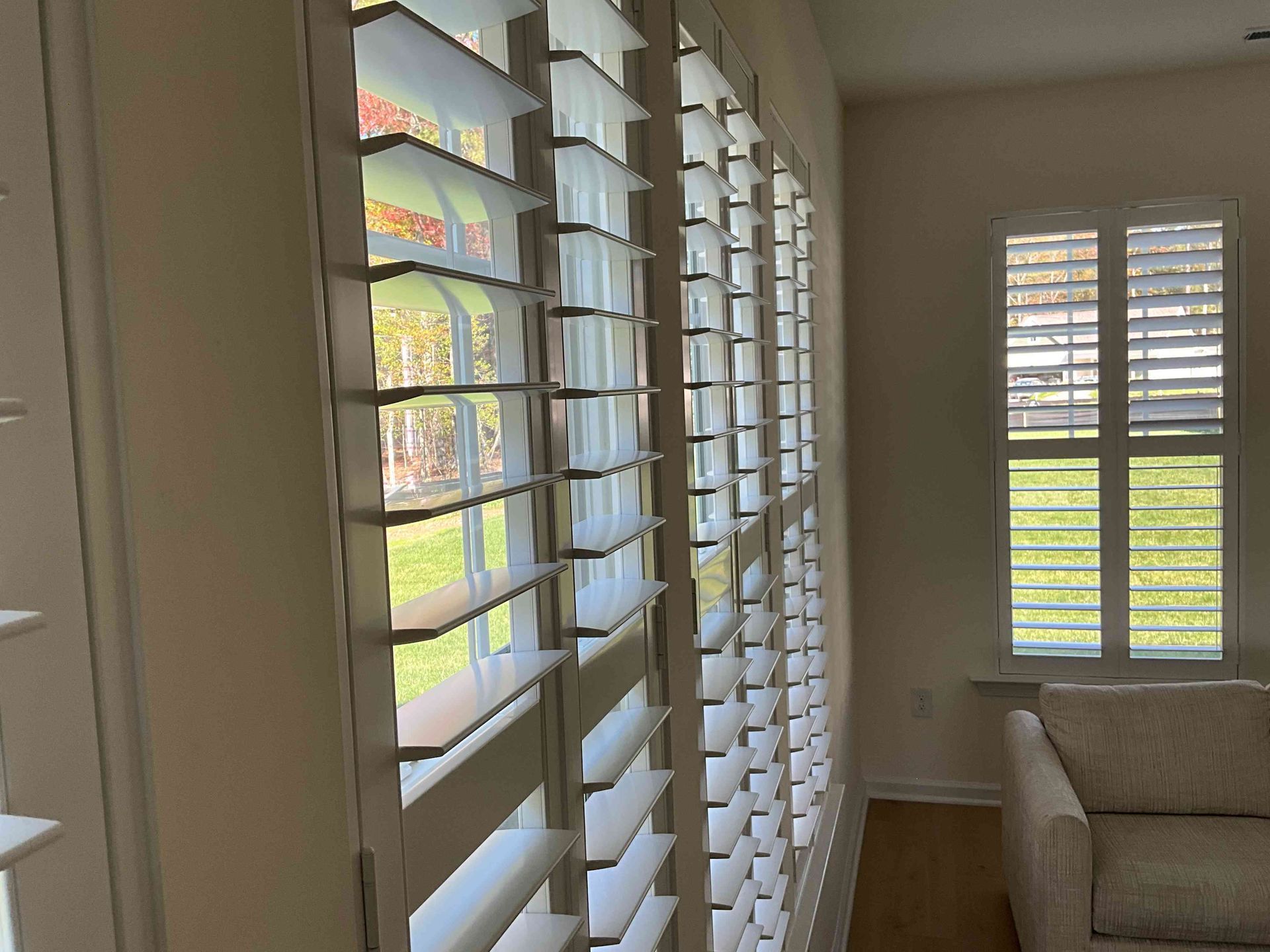 Sunlit hallway with white plantation shutters and a beige armchair by the window