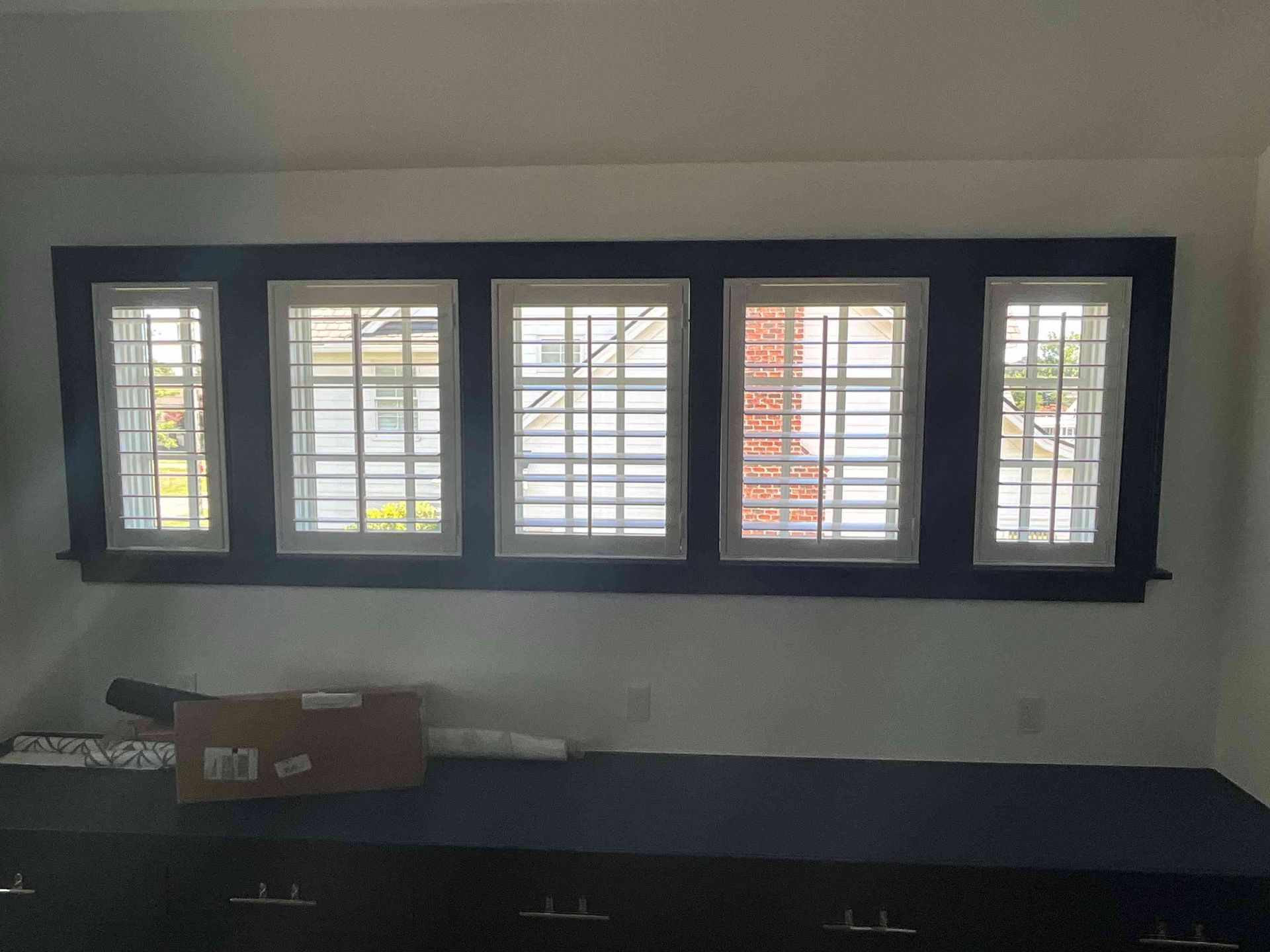 Window with five barred panes above a dark countertop in a plain room.