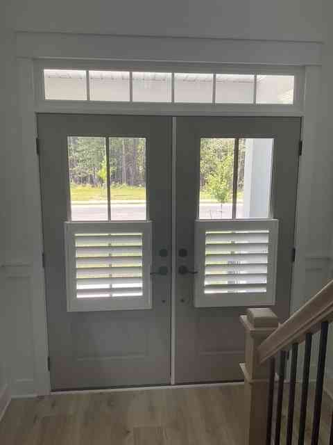 Front entry with white double doors, sidelights, and a staircase on the right.