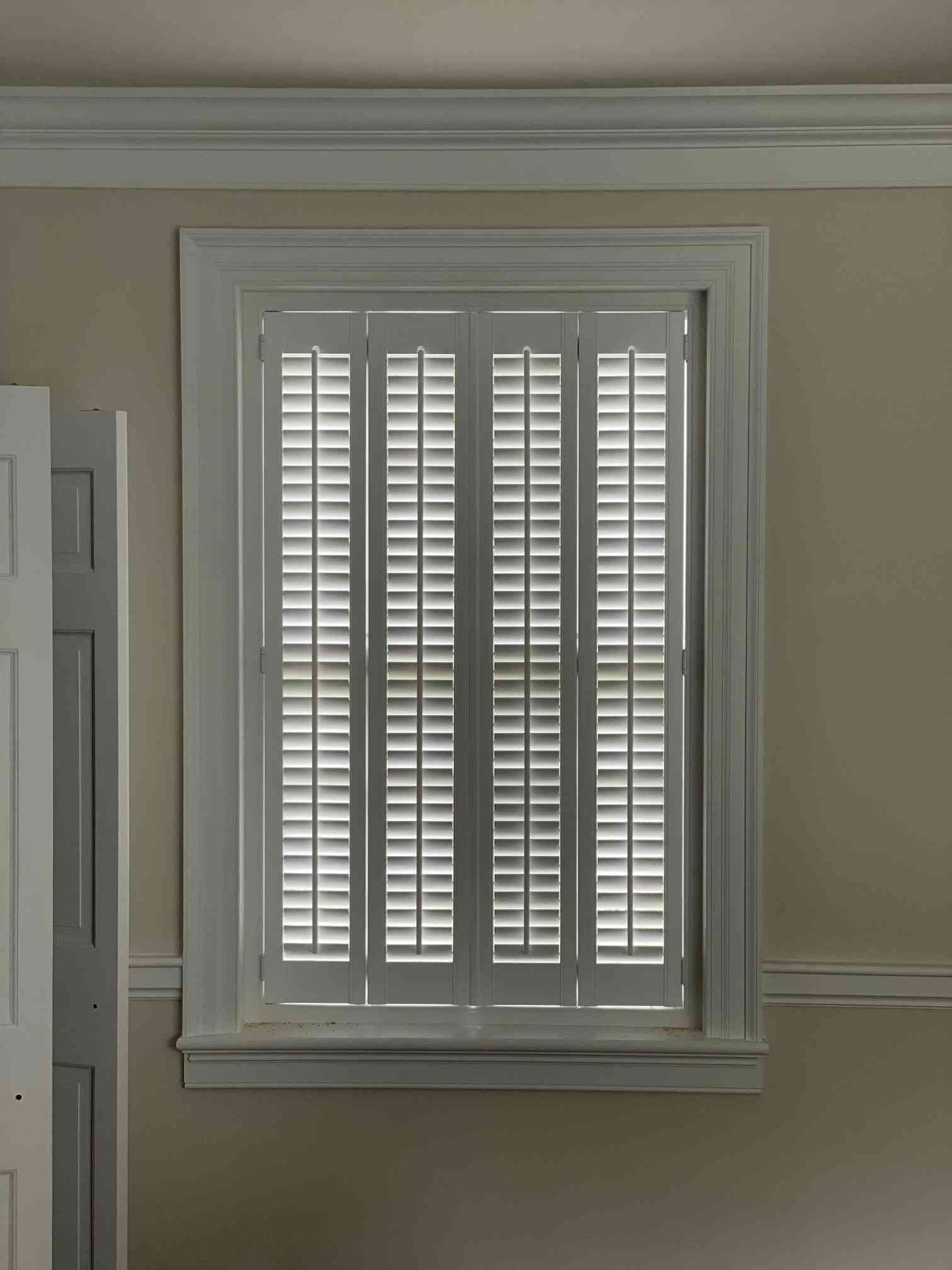 White shutters covering a window in a beige room