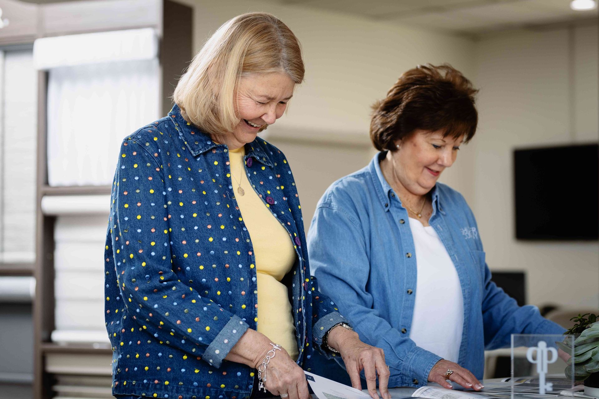 Two women standing in a kitchen, smiling while preparing food together
