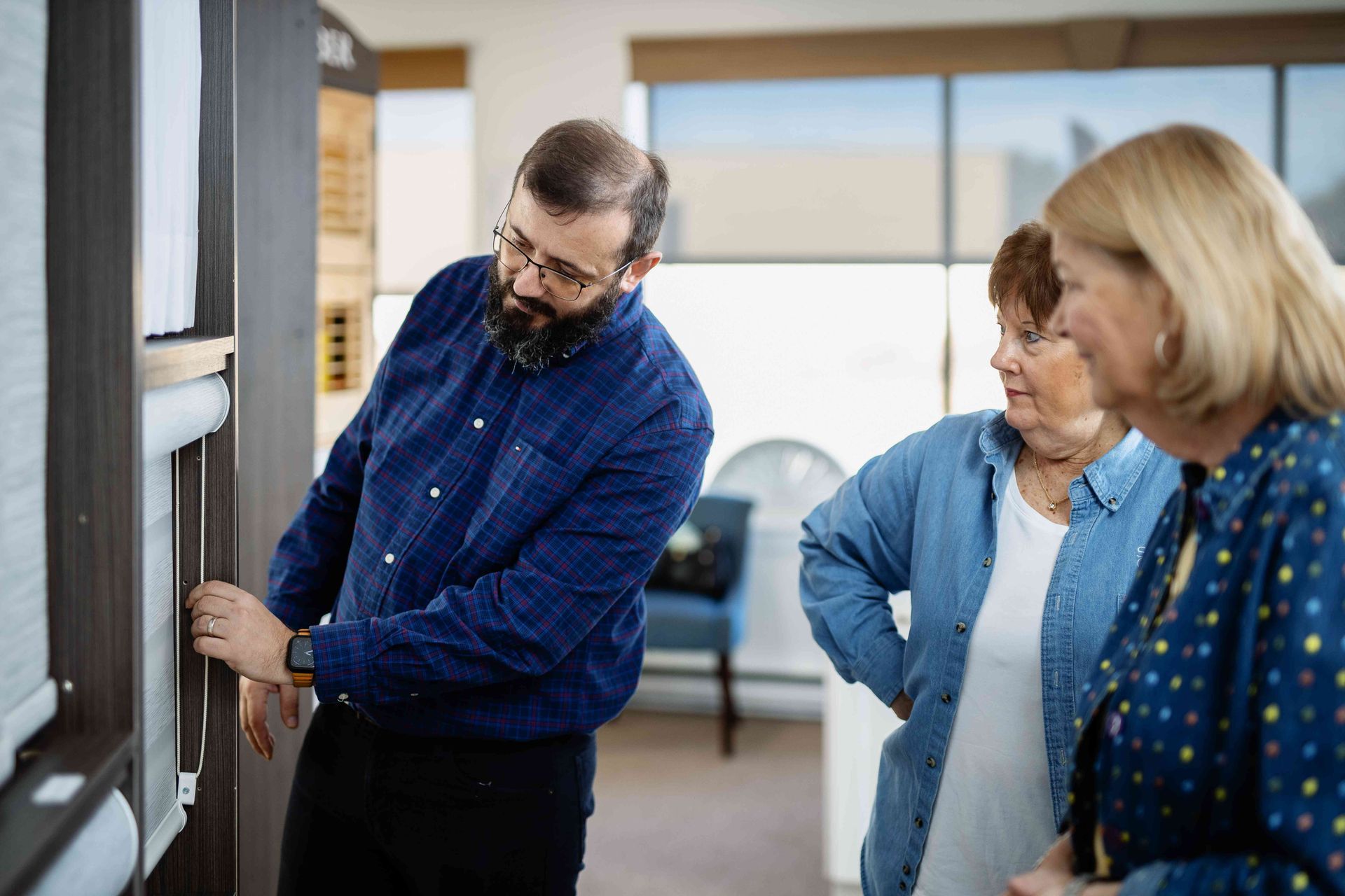 Two people examining a wall display while a man points at it in a bright office setting