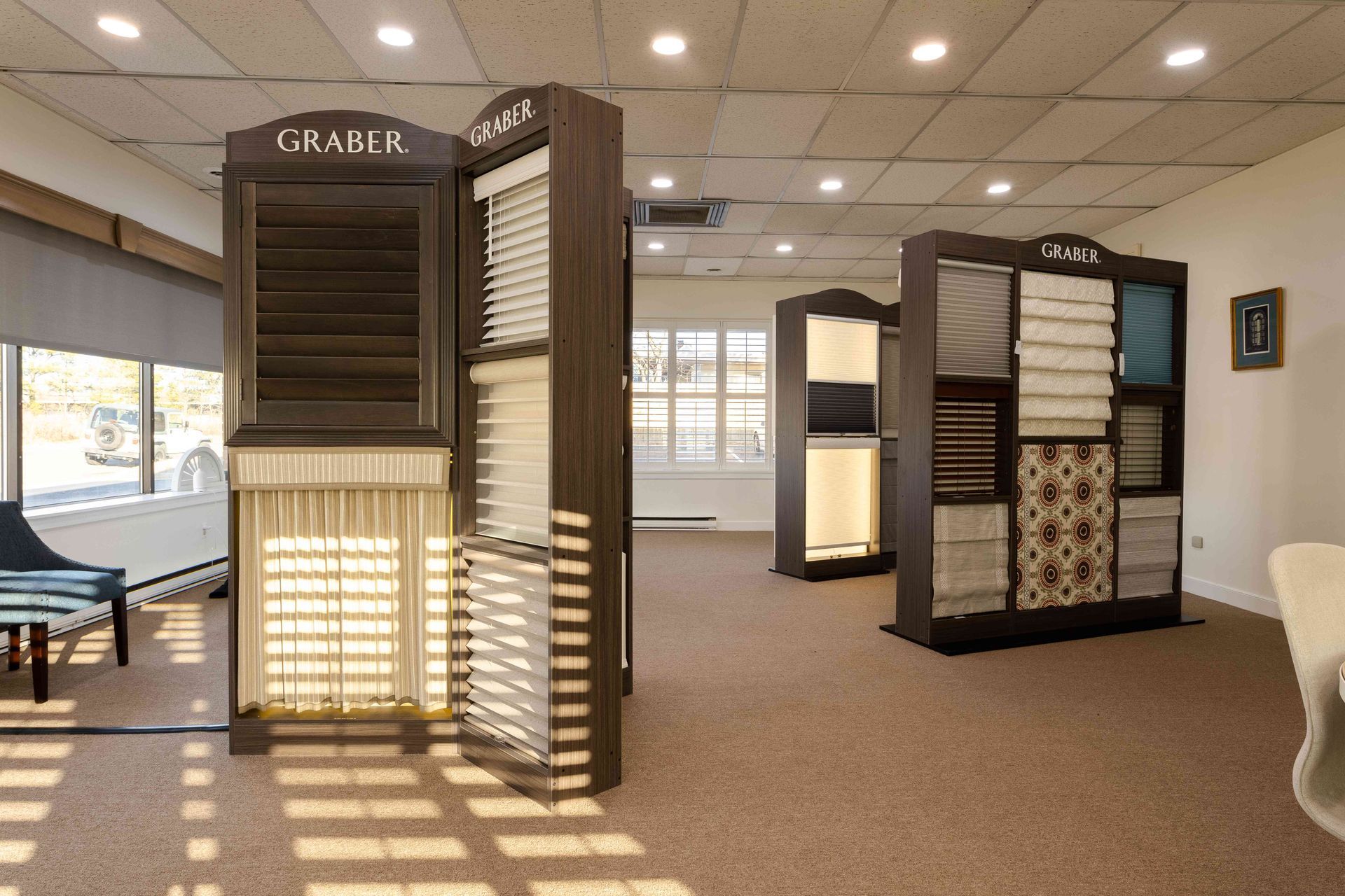 Showroom with carpet samples displayed on freestanding racks in a bright carpet store.