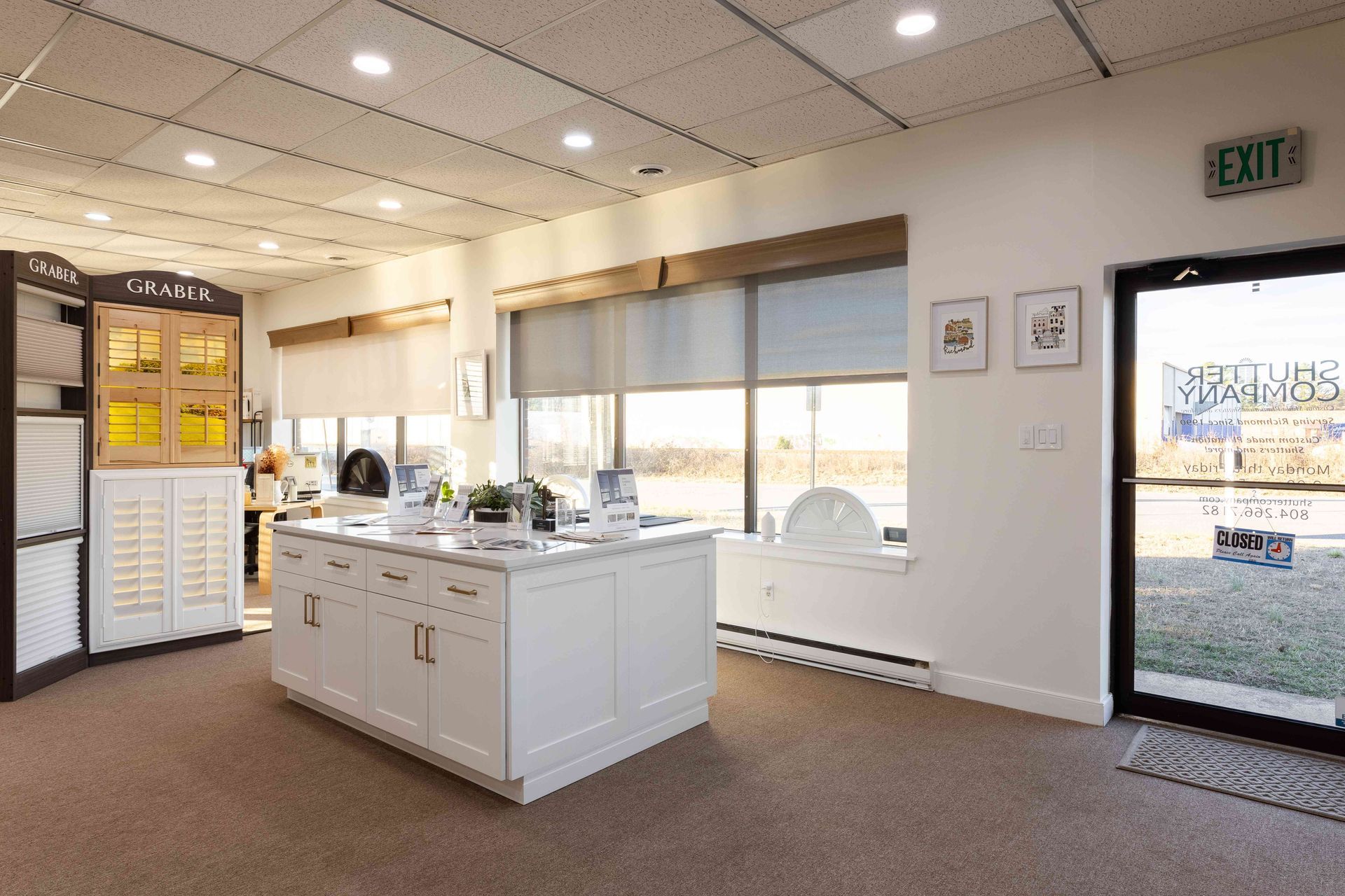 Bright showroom interior with white display island, large windows, and front door entrance.