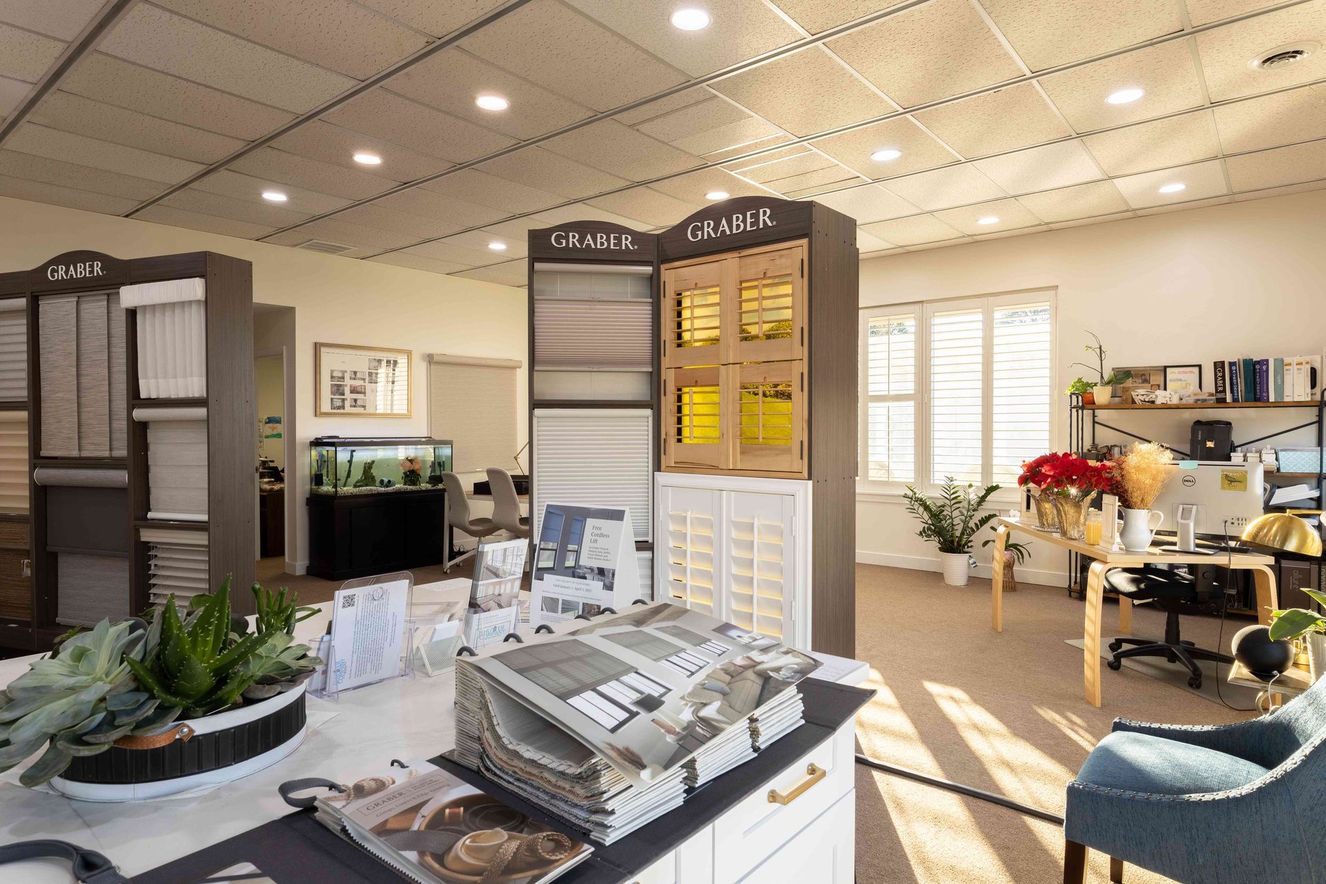 Bright showroom with display panels, office furniture, and sunlight through large windows.
