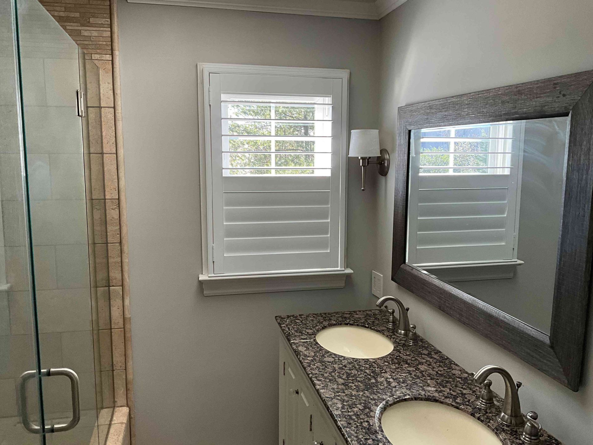 Bathroom vanity with granite countertop, mirror, sink, and window with white shutters