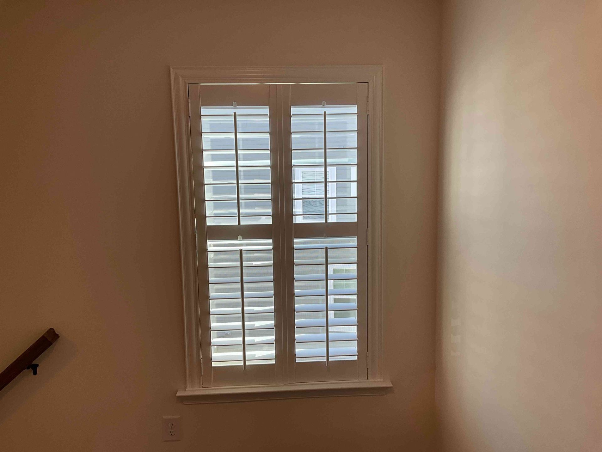 White window with shutters in a beige wall inside a stairwell