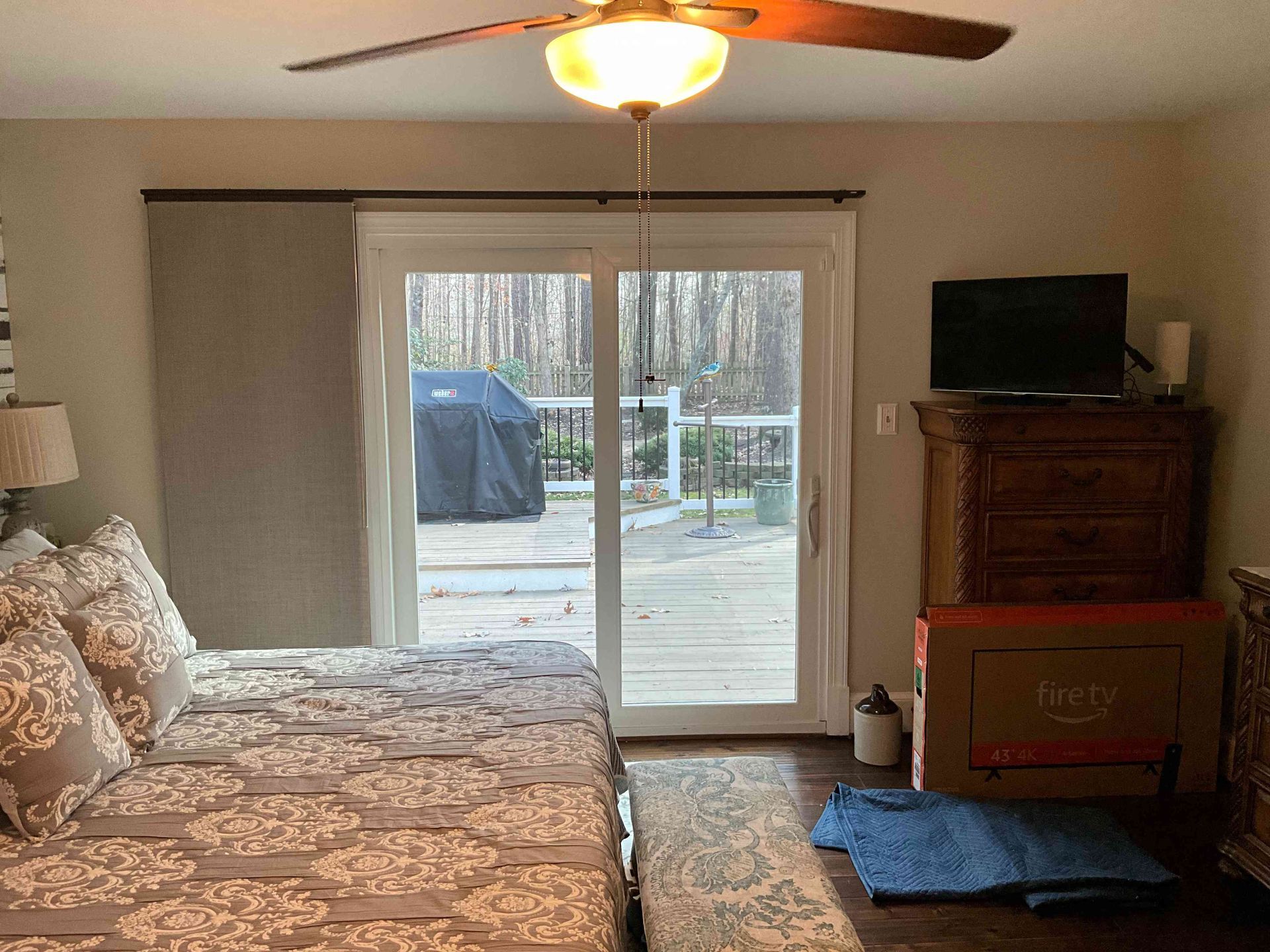 Bedroom with patterned bedspread, sliding glass doors to deck, and TV on dresser.
