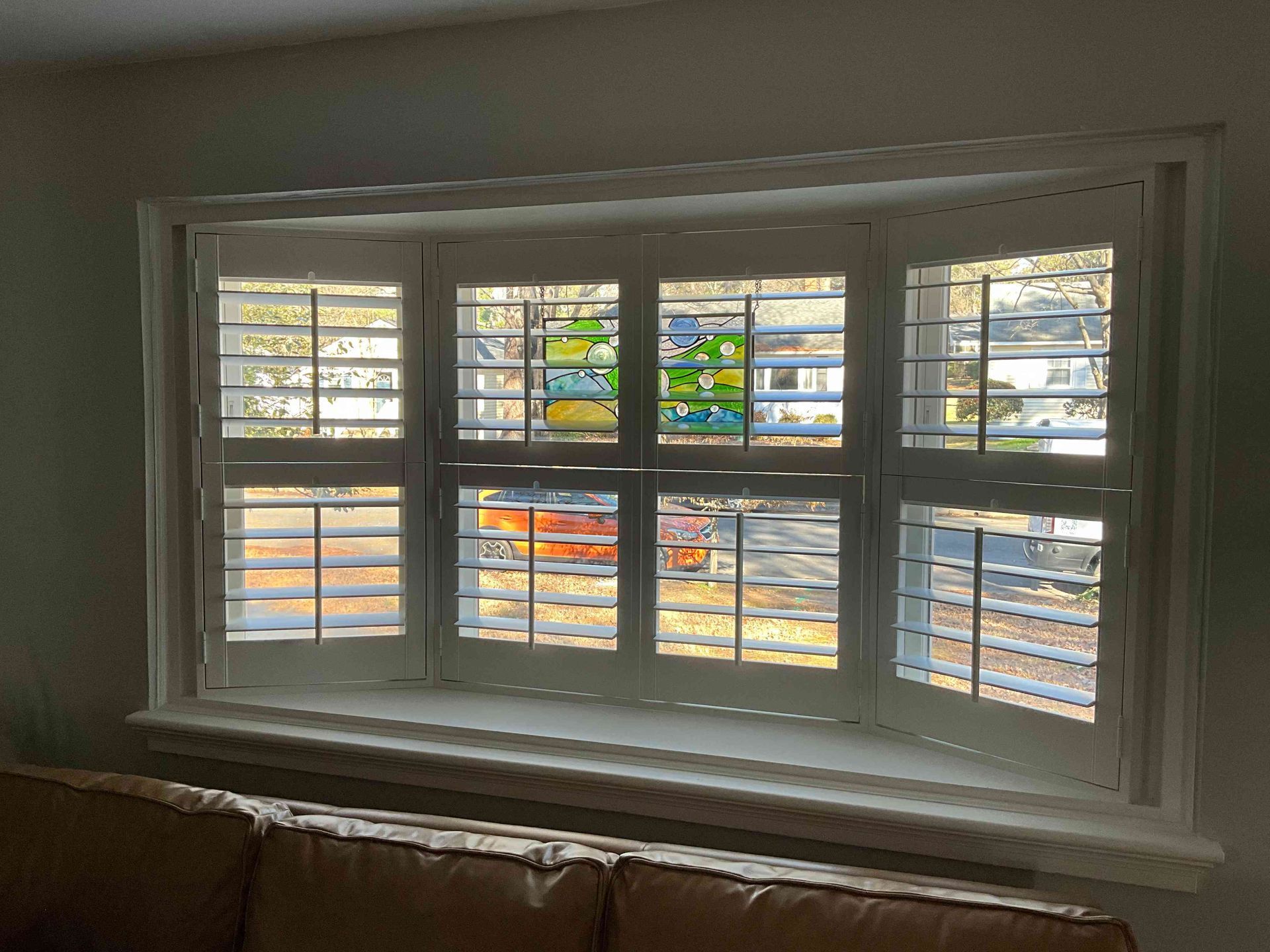 Living room bay window with white shutters, looking out onto a snowy street