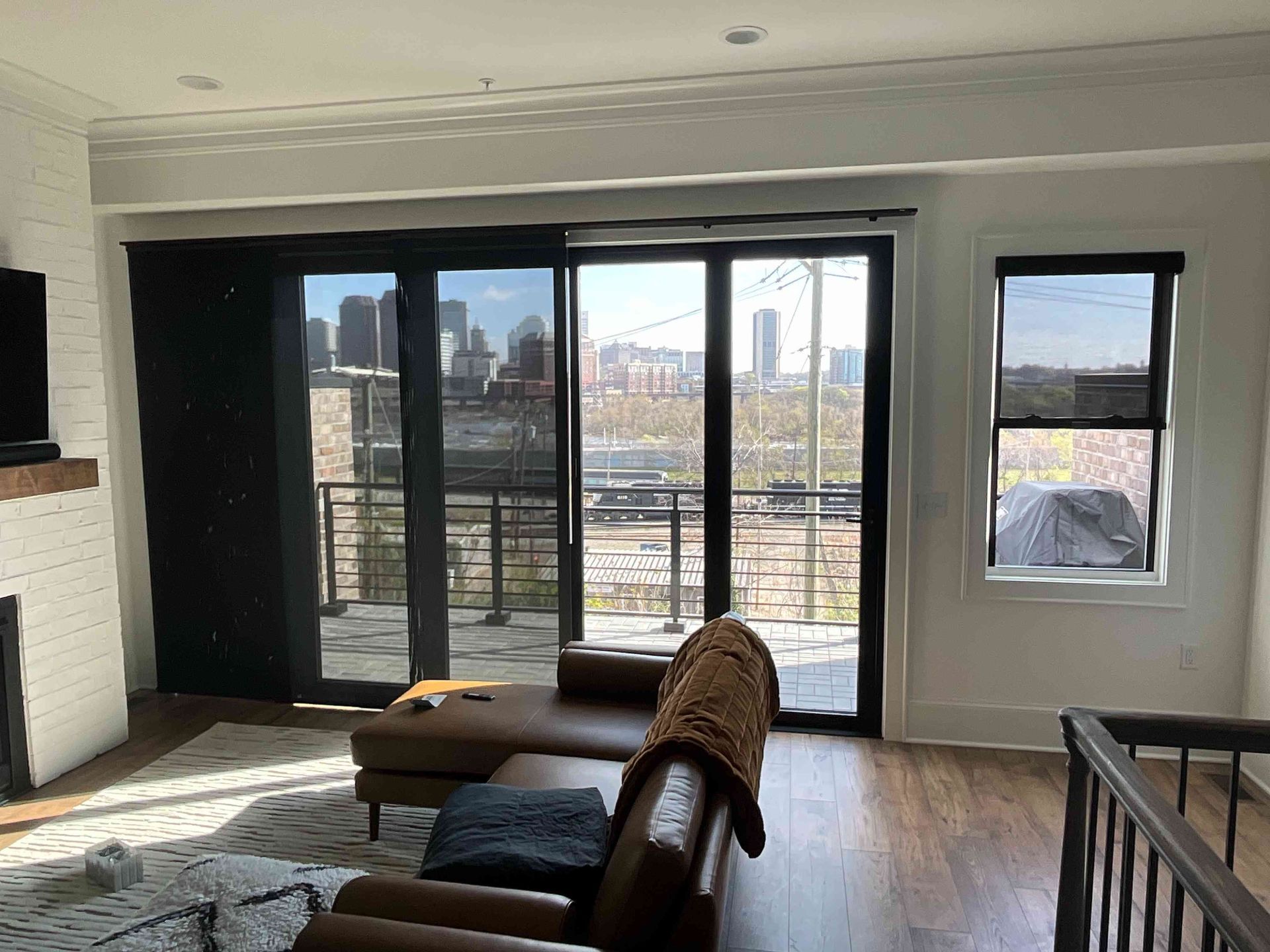 Living room with large glass doors opening to a city view, sofa, coffee table, and hardwood floors