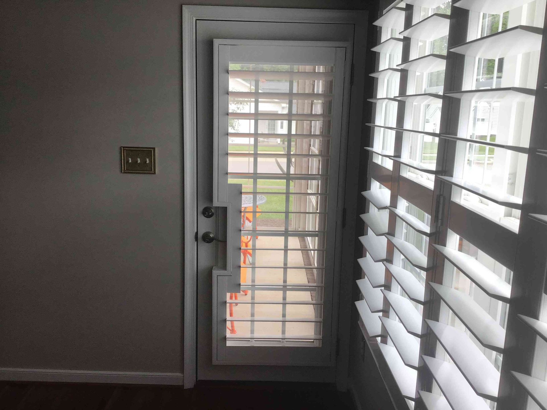 Dim interior hallway with a glass door and white window blinds letting in daylight