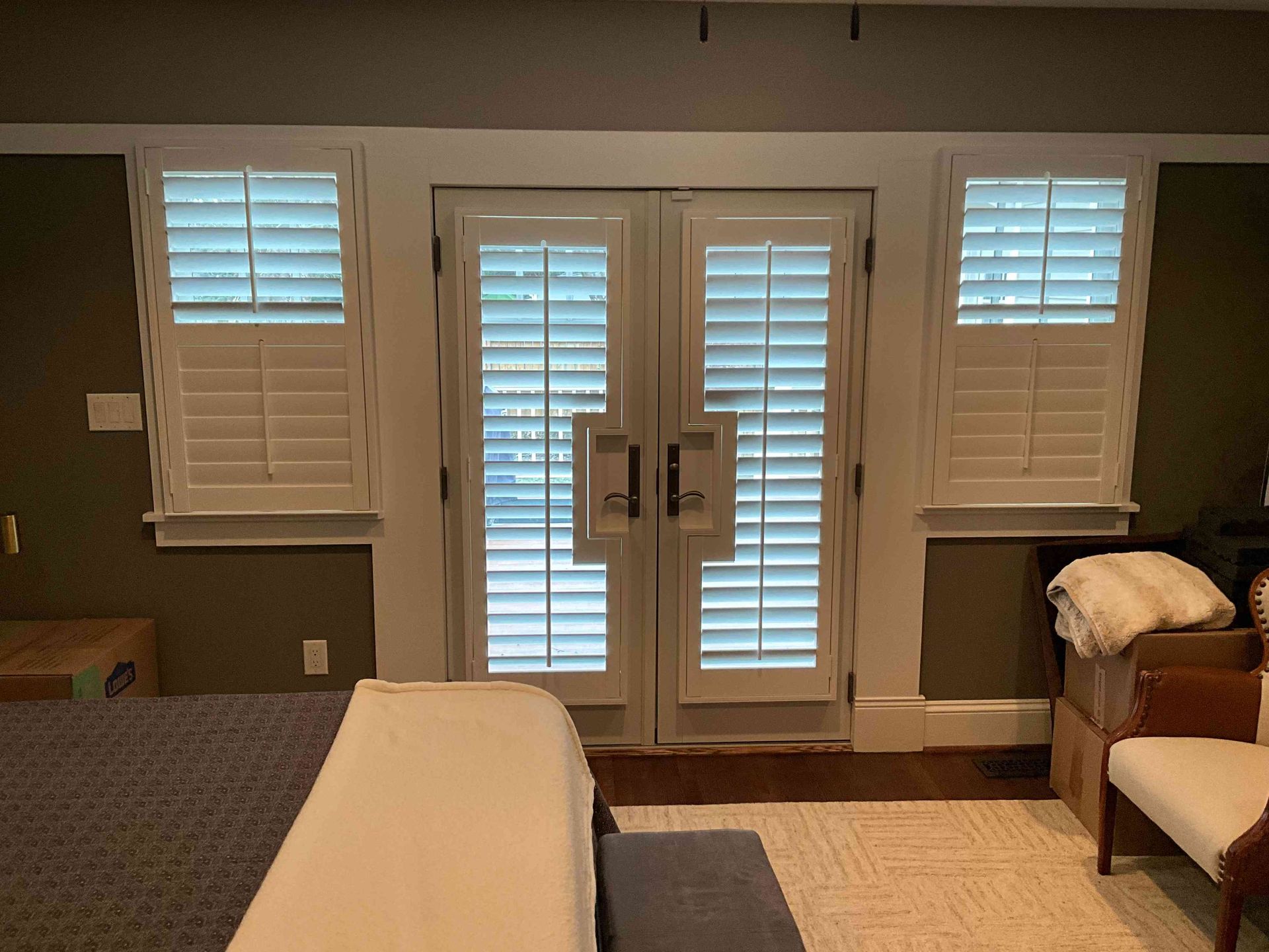 Living room with white shutters, French doors, a beige sofa, and a fireplace on the right
