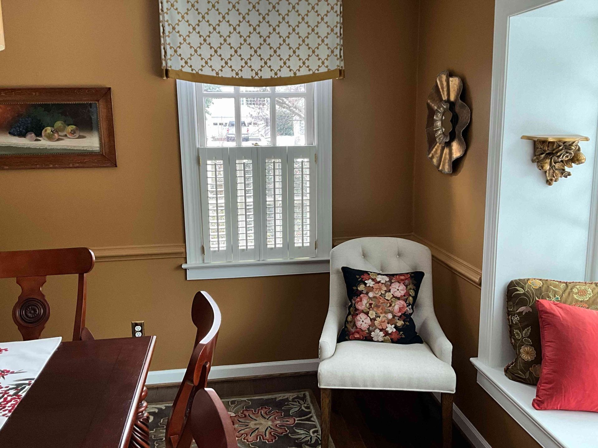 Dining nook with white chair, wooden table, window, and decorative wall art in a beige room