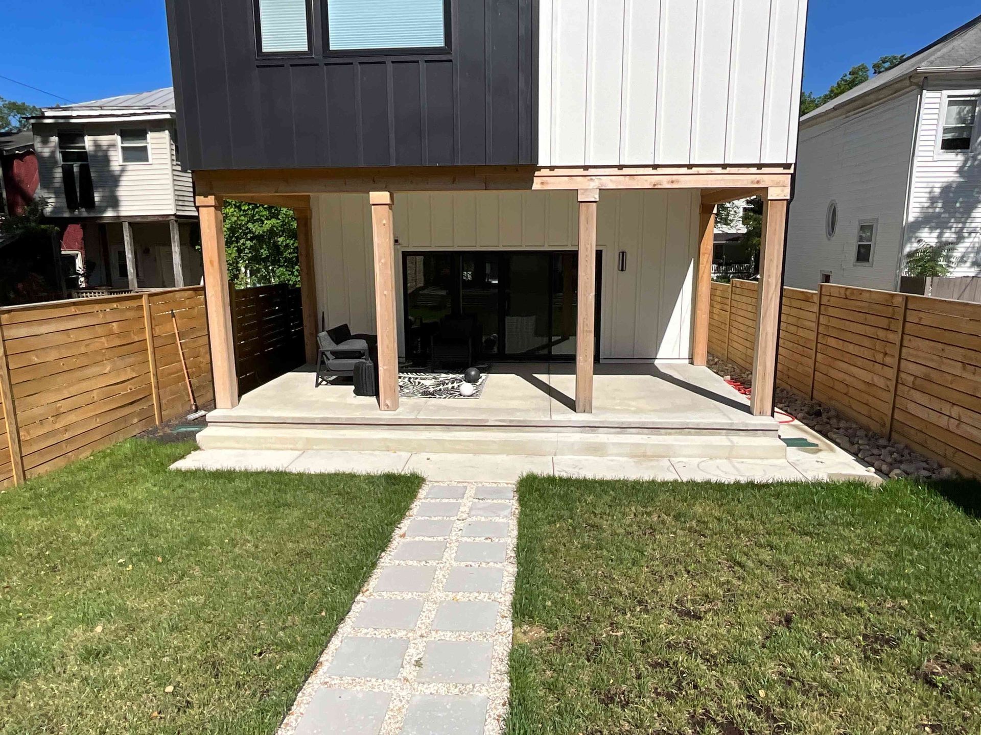 Backyard patio with sliding doors, concrete path, and fenced grass yard