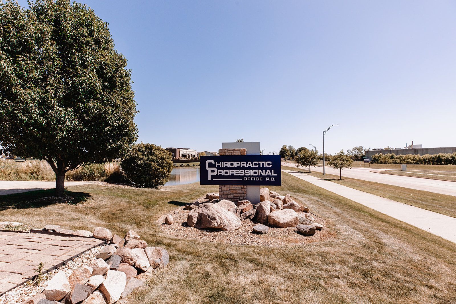 A sign for a chiropractic office is sitting in the middle of a grassy field