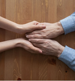A man and a woman are holding hands on a wooden table.