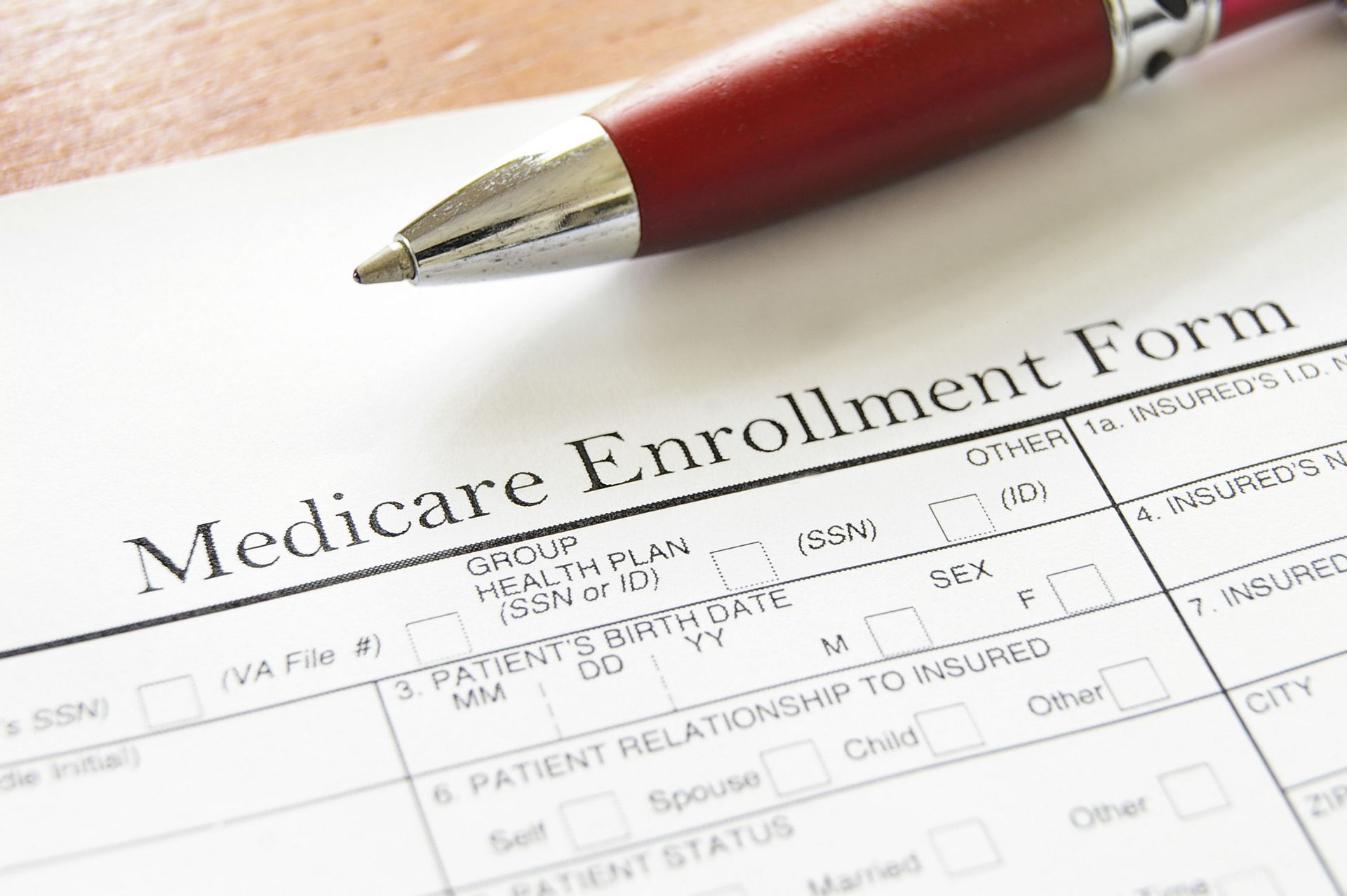 A red pen is sitting on top of a medicare enrollment form