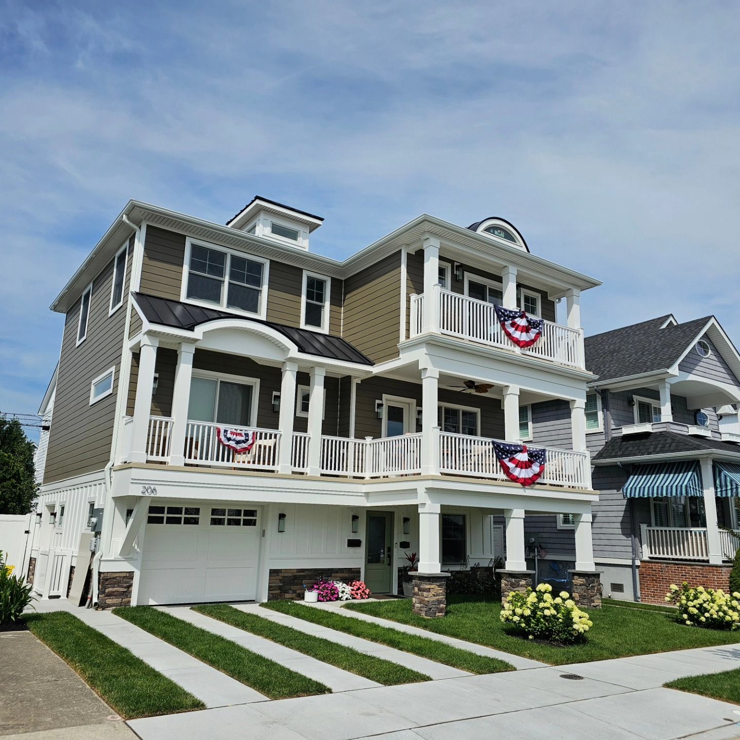 Three-story house with white balconies and brown siding. American flag bunting hangs from the railing.