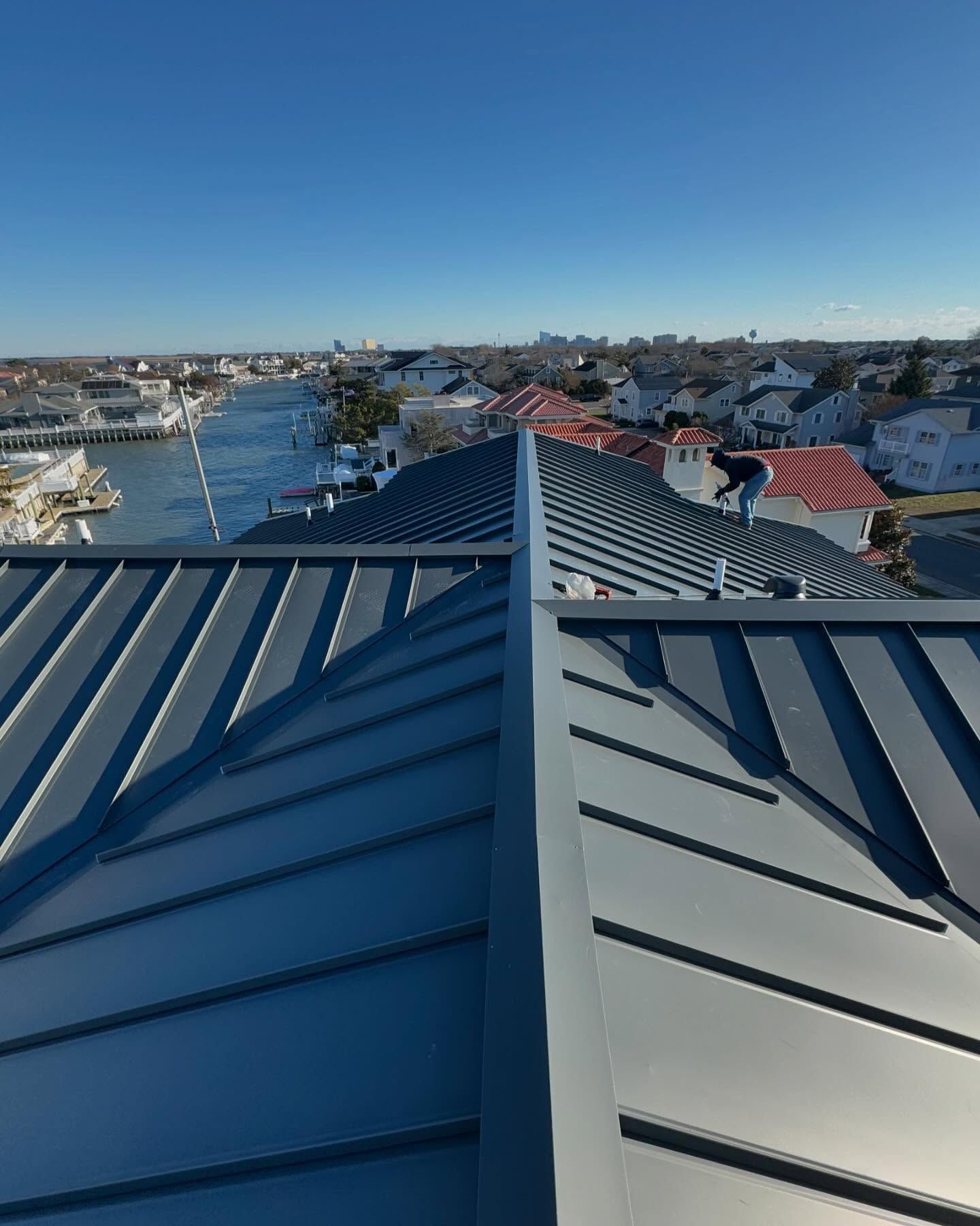 View from a metal roof towards a harbor and town. The sky is blue, and the roof is gray.