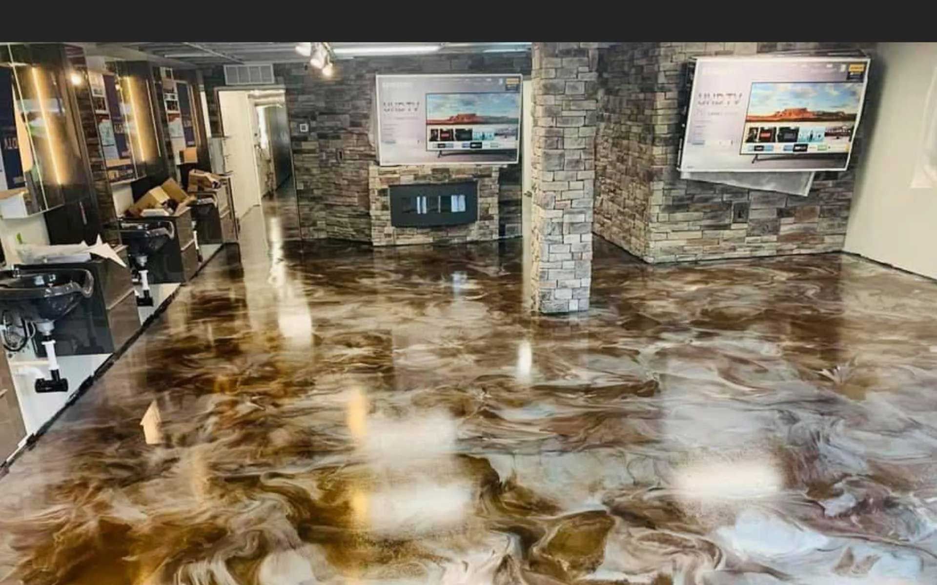 Metallic epoxy flooring in a showroom with stone walls and mounted televisions.