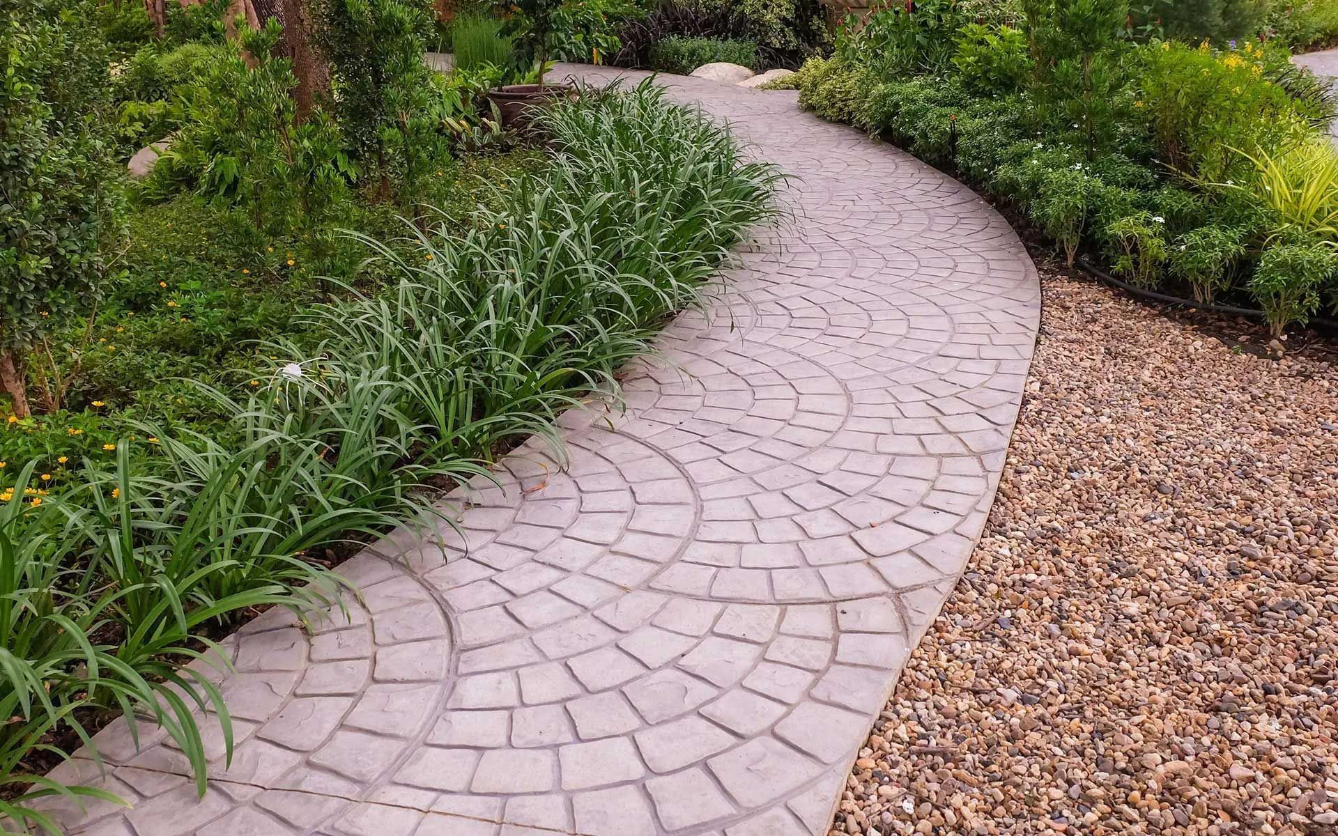 Curved cobblestone pathway through a garden, with plants on either side.