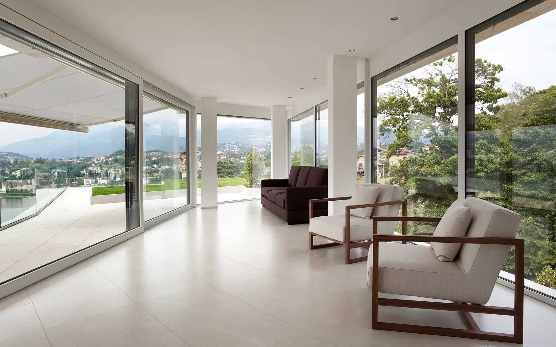 Modern living room with large windows, city view, and brown and white furniture.