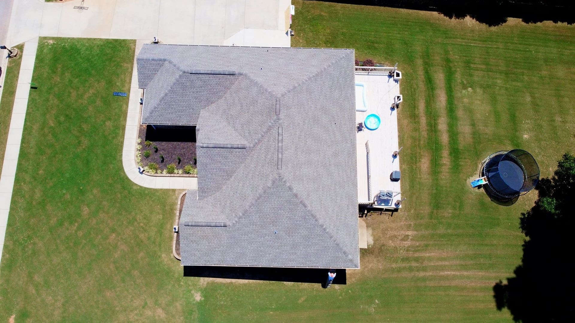 An aerial view of a house with a trampoline in the backyard.