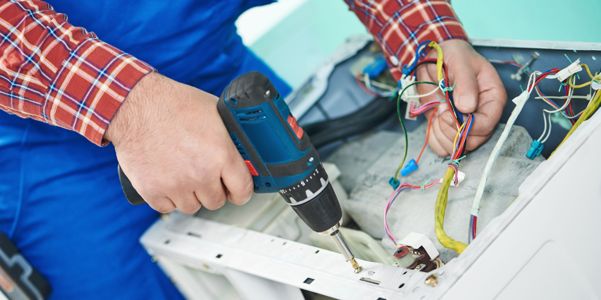 Commercial laundry equipment maintenance being performed on washer using drill