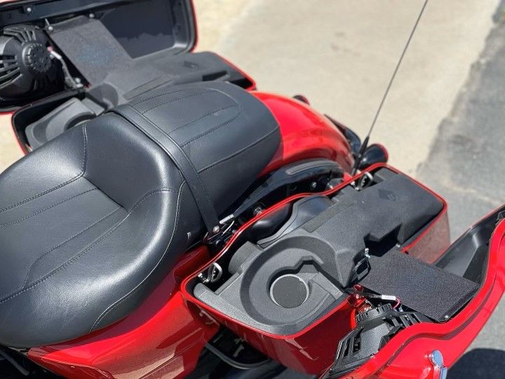 A red motorcycle with a black seat is parked on the side of the road
